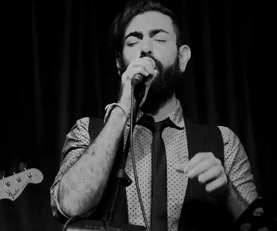 Ferhat Öz singing into a microphone on stage